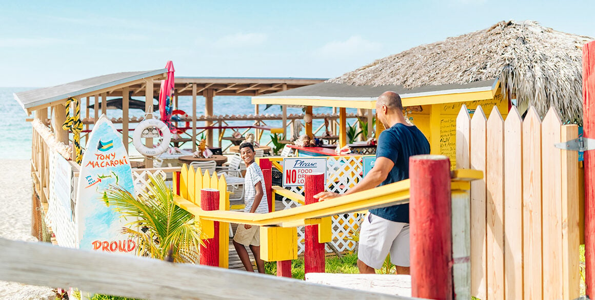 Two people walking toward a colorful beach bar