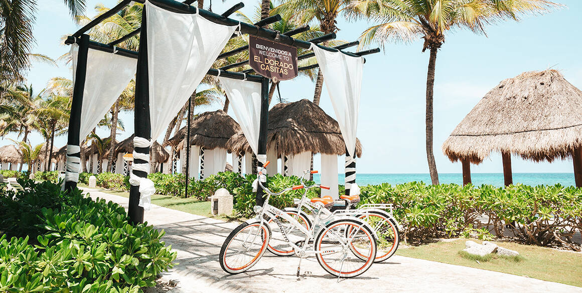 Two bicycles on a sidewalk in front of a gazebo with curtains billowing and ocean views