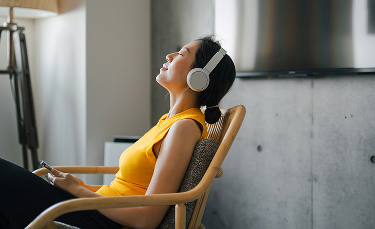 A woman relaxing, leaning back in her chair, with headphones on