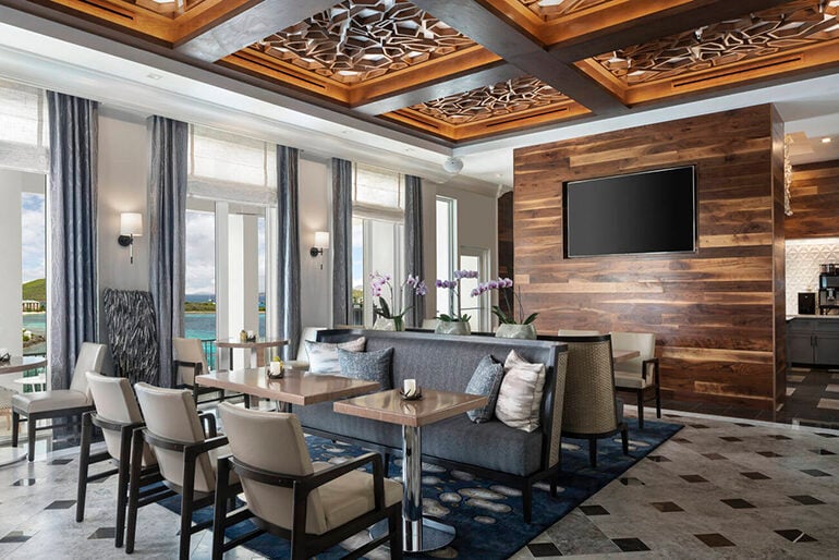 Modern dining room with dark wood and navy accents, including a dark wood statement wall with a TV and dark wood coffered ceilings with black beams