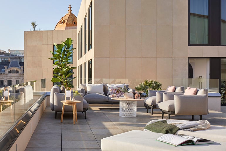 Tiled rooftop with plush chairs for lounging.