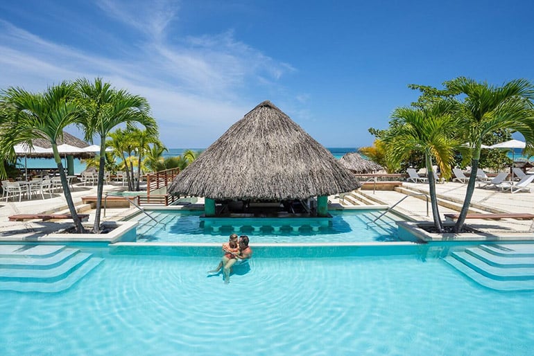 A couple canoodling at a pool bar hut at Couples Swept Away in Jamaica