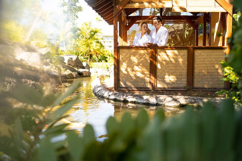 A couple in bathrobes a wooden outdoor massage cabin 