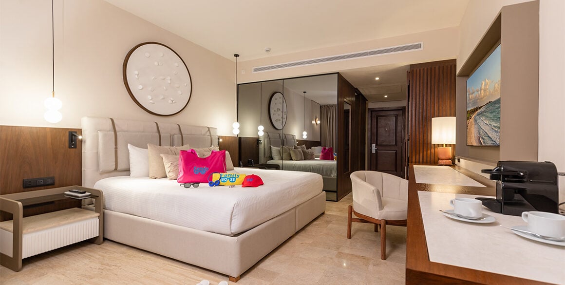 Large hotel suite with a king bed with bright colored children's toys on it