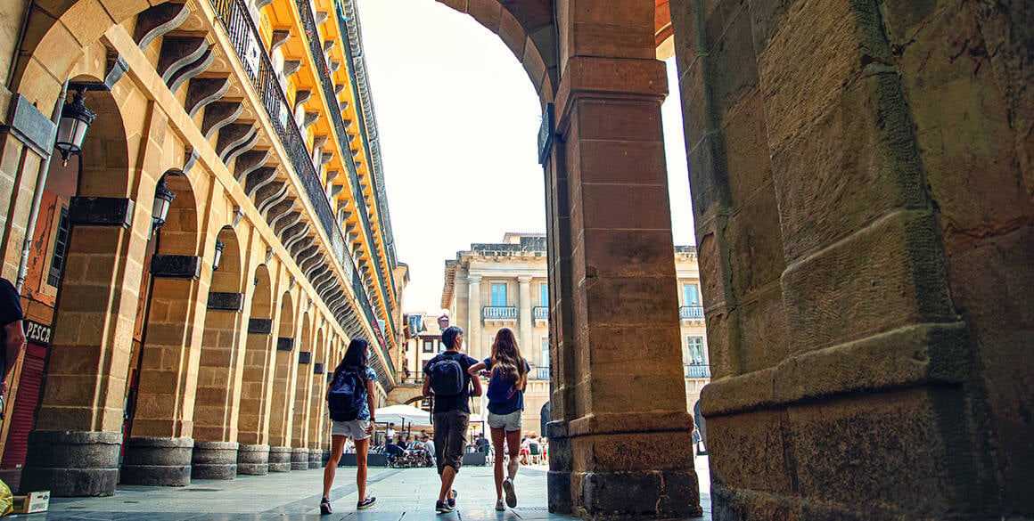 Couple walking through a shaded building into a European courtyard