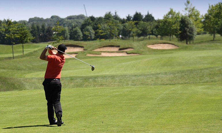 A golfer swinging his club on the green