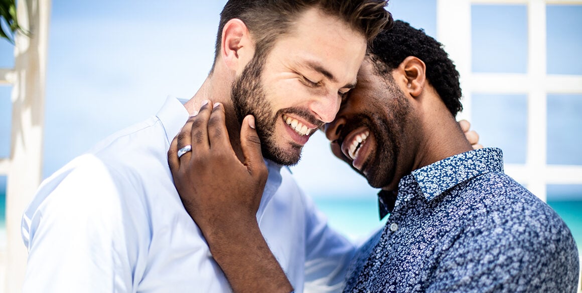 A white and black man tenderly embrace 