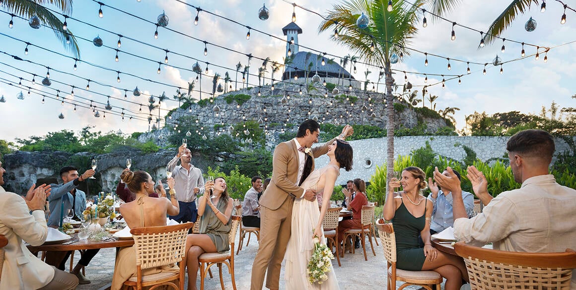 Bride and groom gazing at each other in a crowd beneath the chapel of Hotel Xcaret