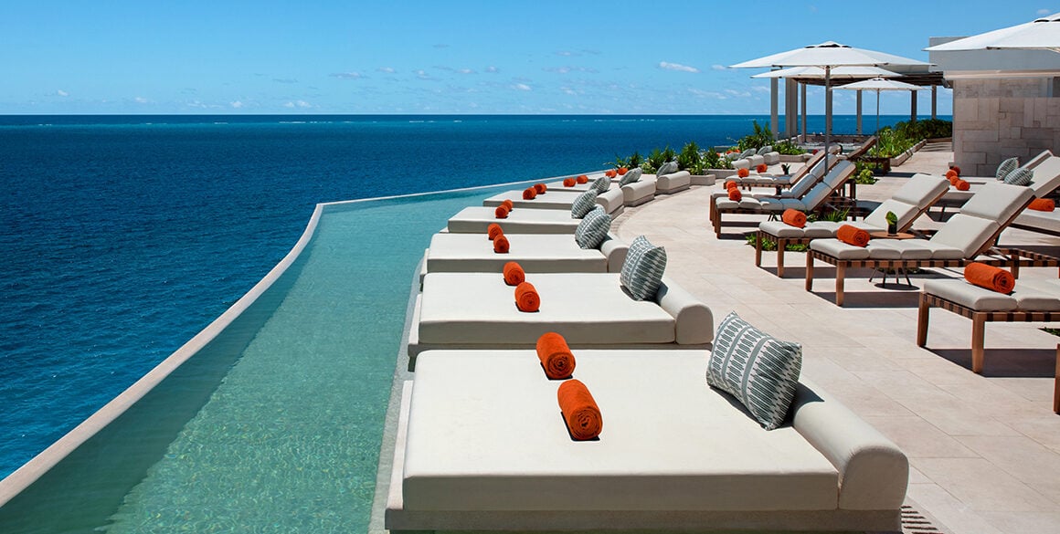 A narrow rooftop infinity pool lined with plush daybeds