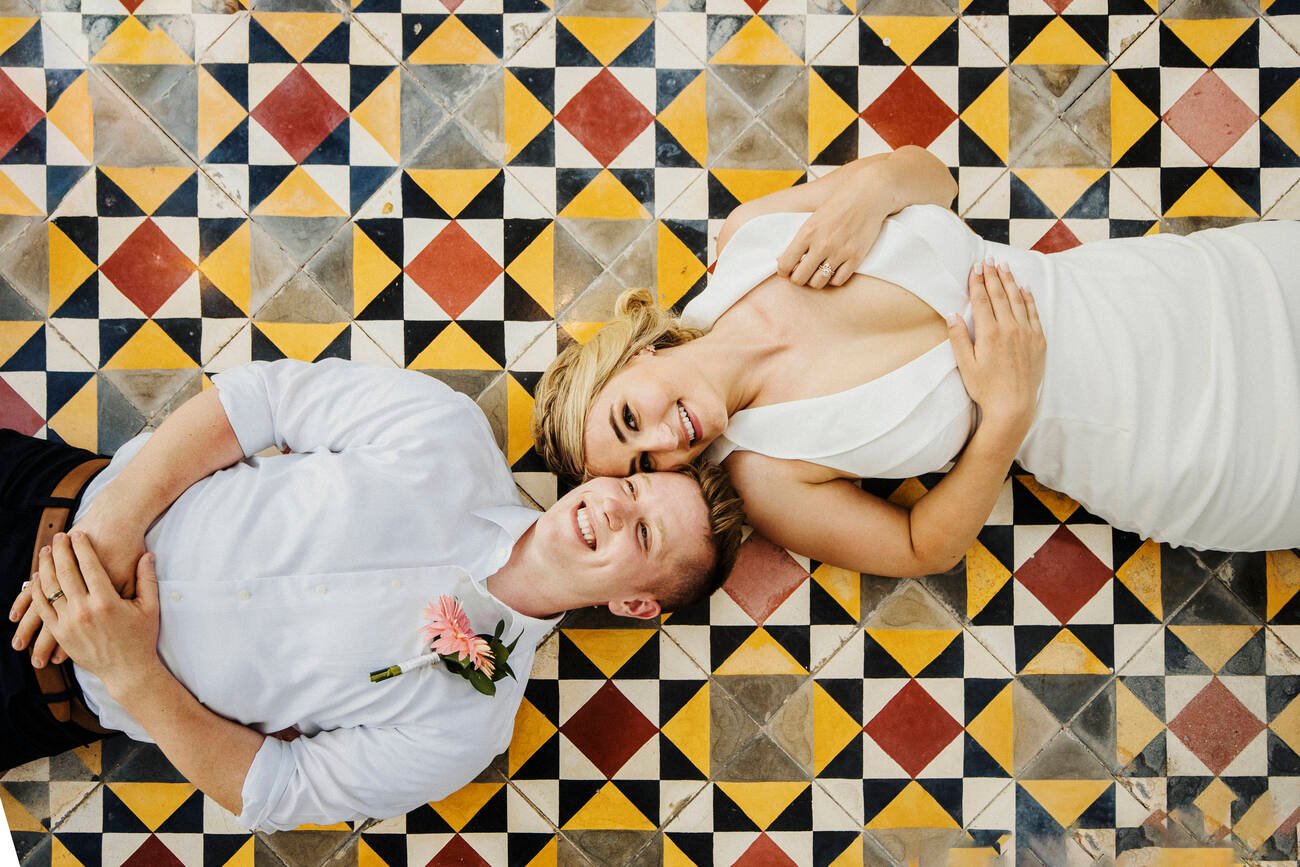 Bride and groom laying on a tile floor