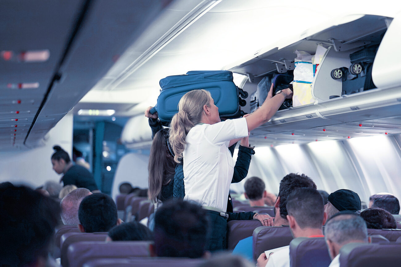 People putting away overhead luggage on a plane