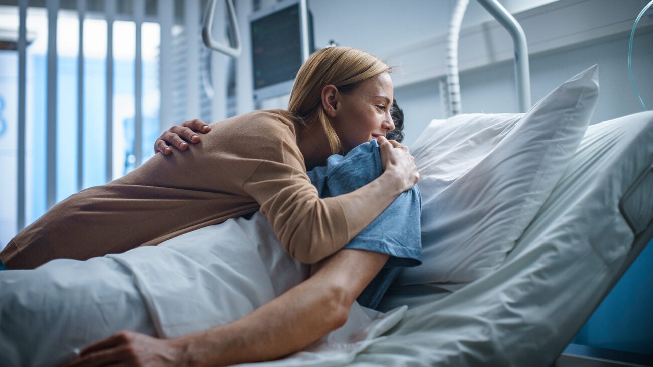 Woman hugging someone in a hospital bed