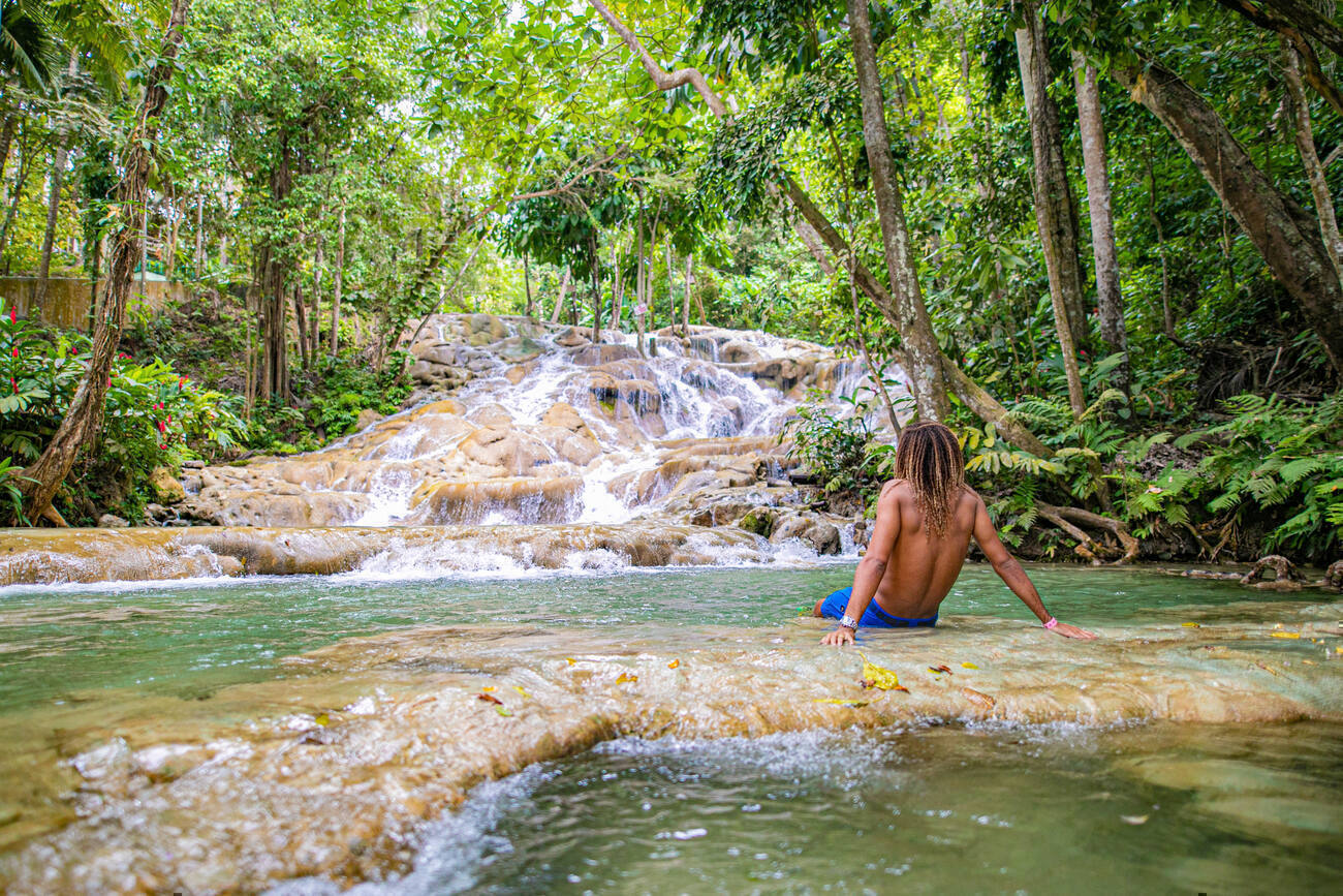 Man sitting in the water looking out at Dunn's River Falls.